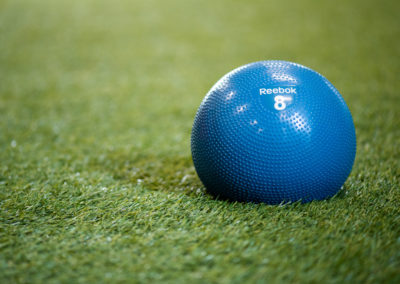 Balle de gym bleue Reebok sur tapis de sol vert, équipement pour l'entraînement fonctionnel.