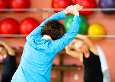 Personne âgée faisant des exercices de stretching avec des ballons de gym en arrière-plan