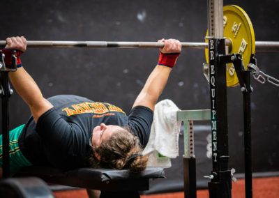 Athlète masculin soulevant des poids sur un banc de musculation en salle de sport