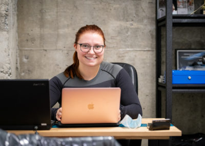 Jeune femme souriante travaillant sur un ordinateur portable Apple dans un espace